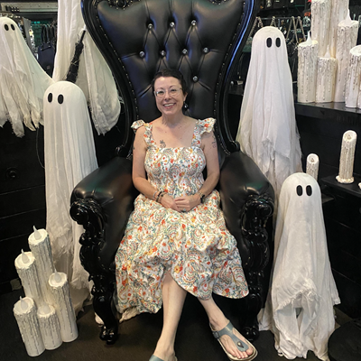Laura Dixon-Caldwell sitting on a black  chair surrounded by ghosts and melting candles